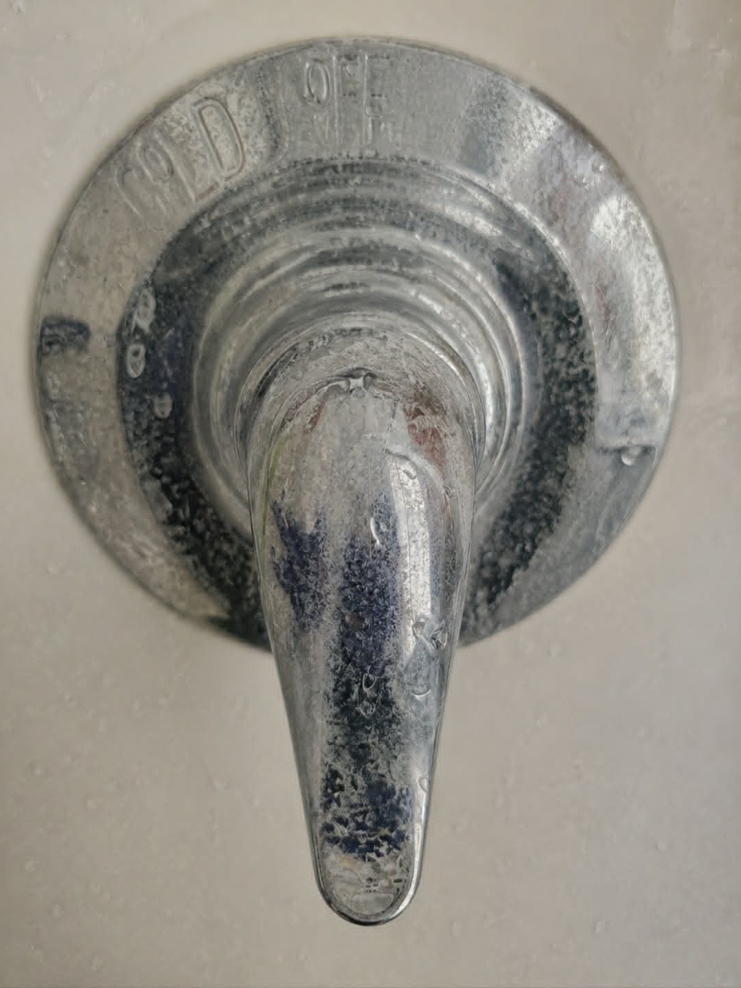 Before picture showing heavy hard water stains, mineral buildup, and soap scum on a chrome shower fixture in St. Louis.